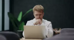 Muškarac koji razmišlja nagnut nad računalo