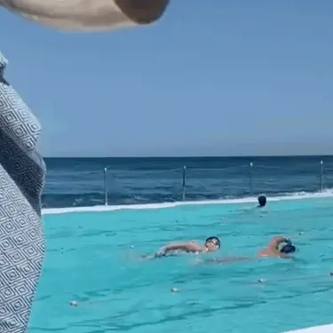 Žena u bazenu koja pliva s mobitelom u ruci