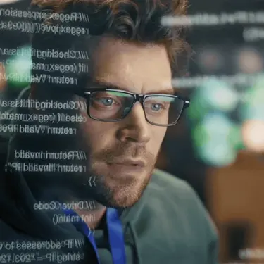 Programer pred računalom i kodovi na ekranu