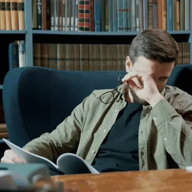 Skidanje naočala u knjižnici i trljanje očiju