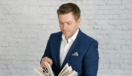 Intelektualac koji lista knjigu i razmišlja