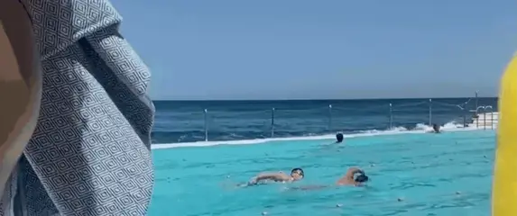 Žena u bazenu koja pliva s mobitelom u ruci