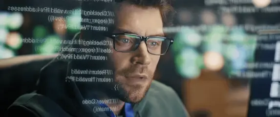 Programer pred računalom i kodovi na ekranu