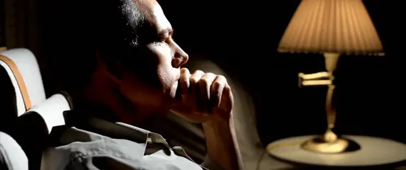 Muškarac koji razmišlja u slabo osvijetljenoj sobi