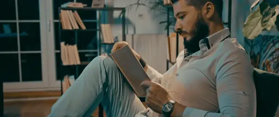 Muškarac na kauču kako čita knjigu