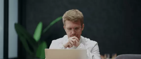Muškarac koji razmišlja nagnut nad računalo