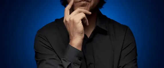 Muškarac kako stoji i gladi bradu pri razmišljanju