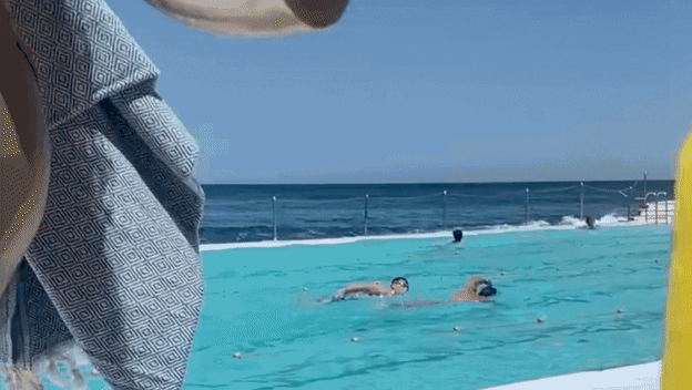 Žena u bazenu koja pliva s mobitelom u ruci