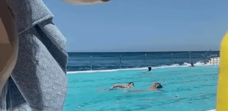 Žena u bazenu koja pliva s mobitelom u ruci