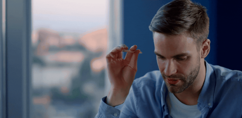 Muškarac koji razmišlja za stolom s olovkom u ruci