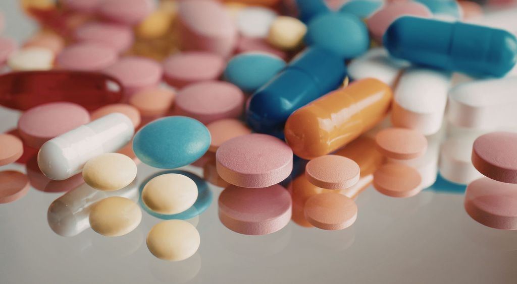 Žena srednjih godina koja drži nekoliko raznih tableta