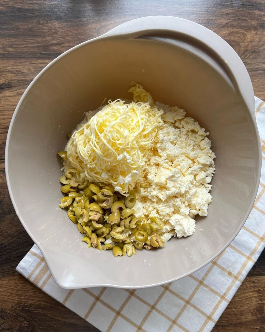 Dodati cijelo jaje, mrvljeni sir, naribani maslac i po želji sitno sjeckane masline.
