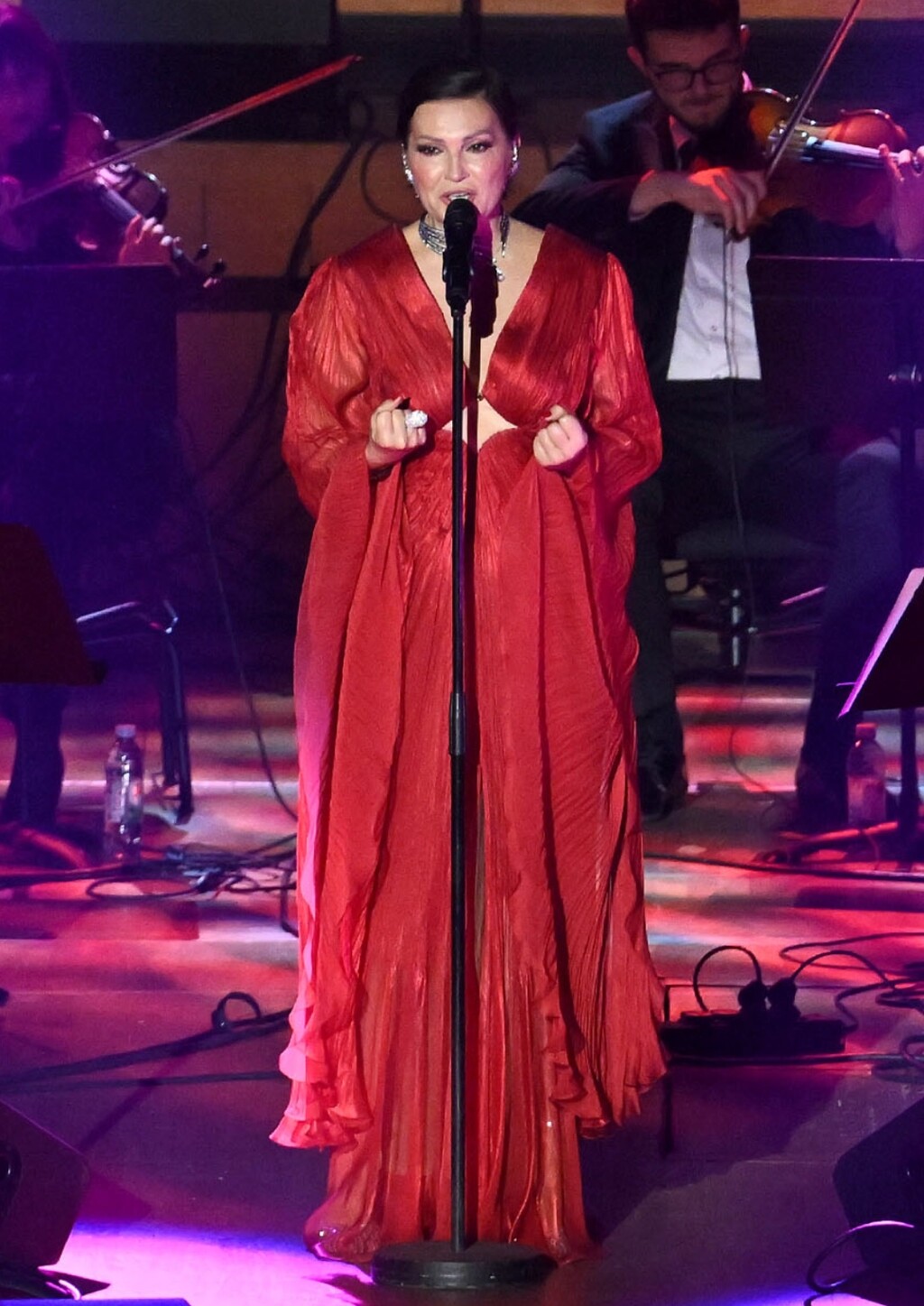 Kroj naglašava siluetu, s dubokim V-izrezom i decentnim izrezom ispod prsiju