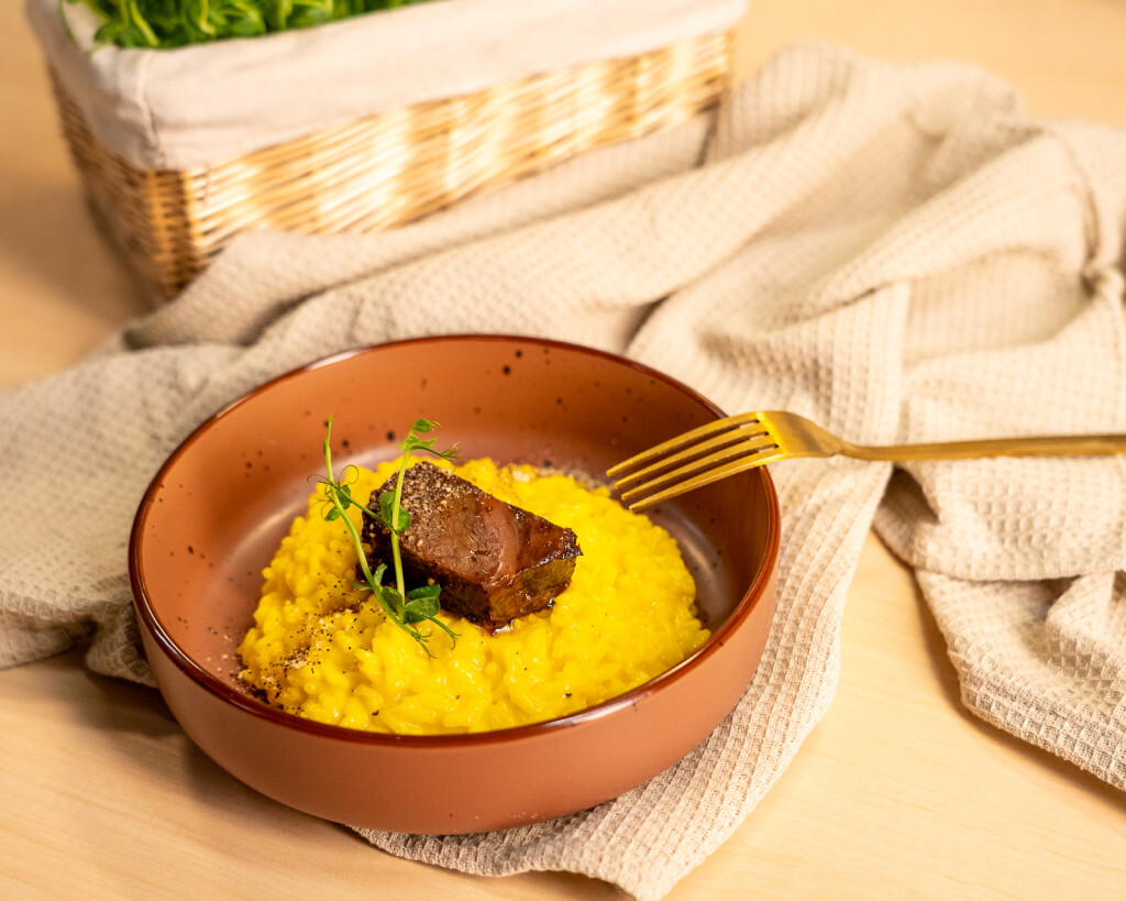 Vibrantan žuti rižoto milanese sa sporo kuhanim goveđim obrazima i prahom od kave i amaretta