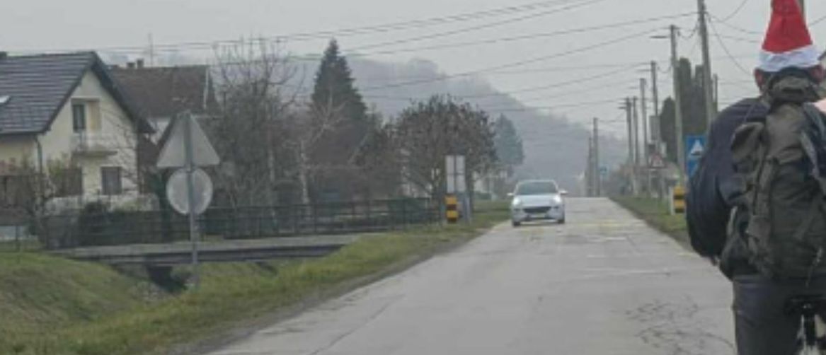 Muškarac s božićnom kapicom na biciklu sa svinjom u torbi