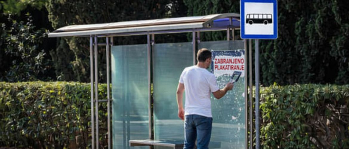 Muškarac koji uklanja natpis zabranjeno plakatiranje s autobusne stanice