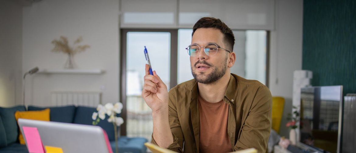 Muškarac za računalom s otvorenom knjigom