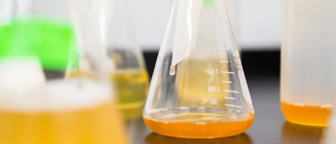 erlenmeyerove tikvice posložena na stolu pune narančaste tekućine u laboratoriju