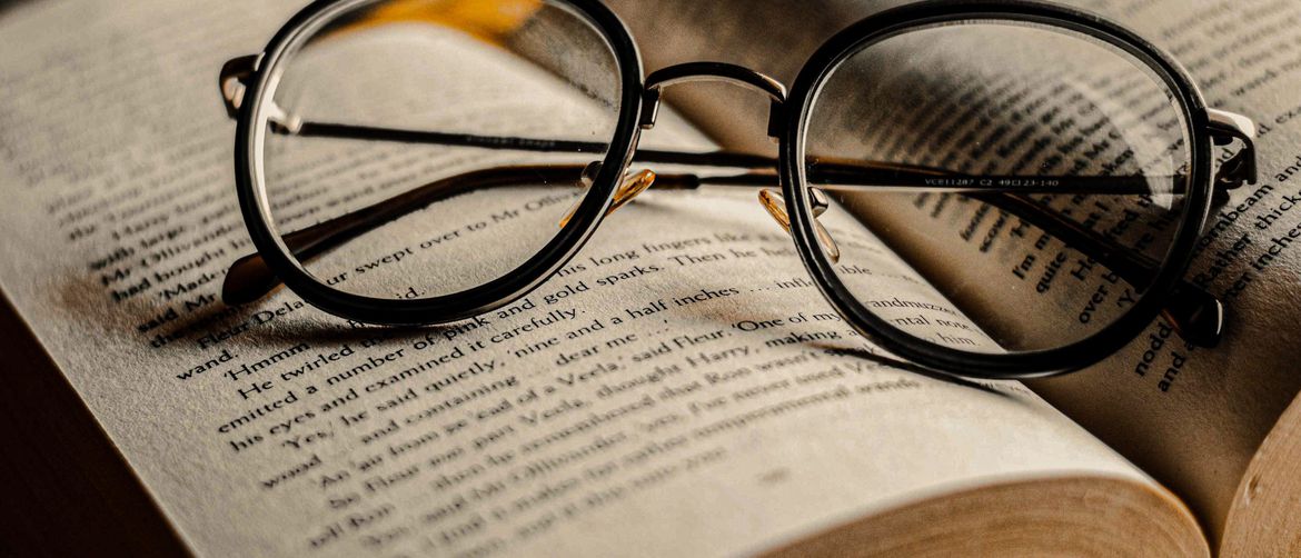 otvorena knjiga s naočalama postavljenim na nju