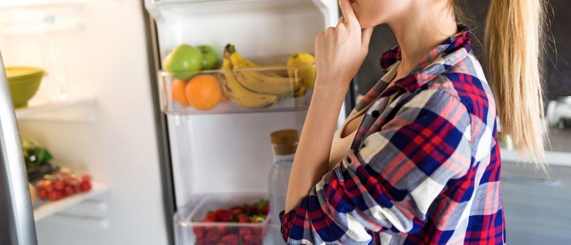 Djevojka zamišljeno gleda u hladnjak