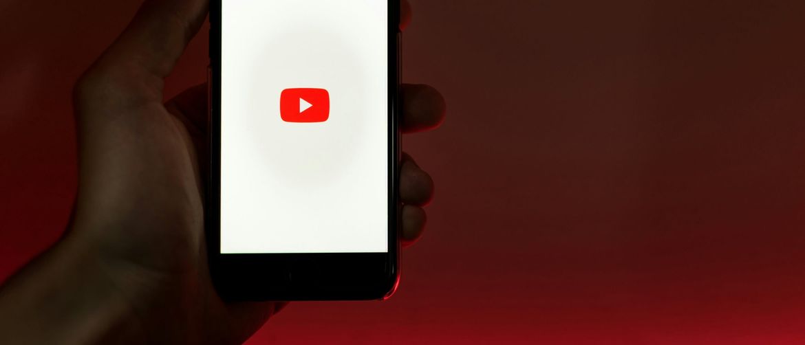 ruka koja drži mobitel s upaljenim zaslonom učitavanja youtubea