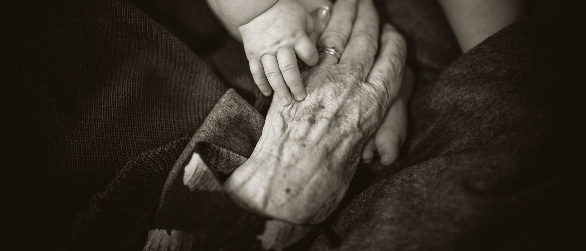 mlada i stara ruka jedna na drugoj koja simbolizira starenje