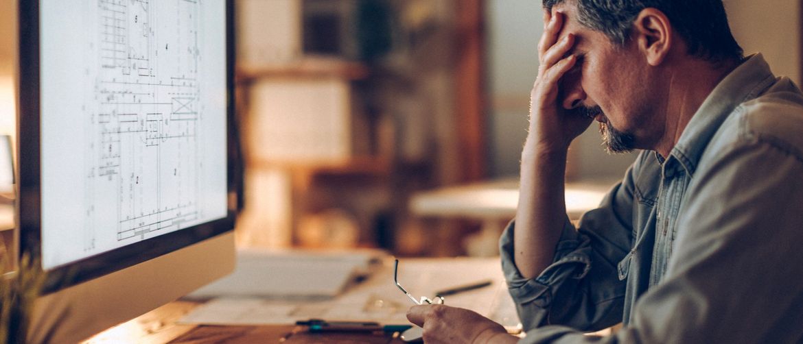 Muškarac koji razmišlja pred računalom i drži se za glavu