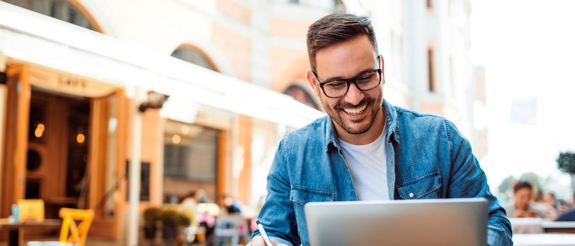 Muškarac koji čita na računalu uz kavu