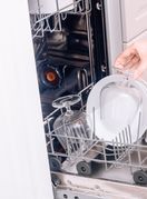 Žena puni perilicu posuđa