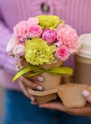 Žena drži cvijeće i kavu