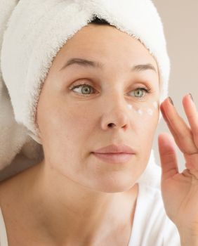 Žena nanosi kremu za područje oko očiju