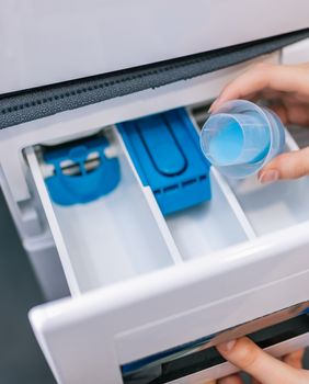 Žena stavlja omekšivač u perilicu rublja