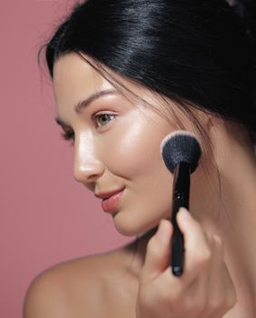 Žena nanosi puder kistom