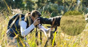 Fotograf u prirodi i mladunče lava skriveno u visokoj travi