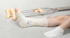 Noga u gipsu i štake pored osobe koja leži na krevetu