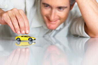 Muškarac se igra s minijaturnum igračkom sportskog automobila