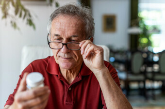 Stariji muškarac proučava kutiju s tabletama, ilustracija