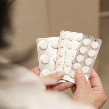 Žena srednjih godina koja drži nekoliko raznih tableta