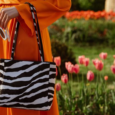 Žena u narančastom outfitu i s torbom sa zebrastim uzorkom
