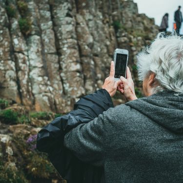 stariji sjedi muškarac kako na izletu u prirodi fotografira krajolik