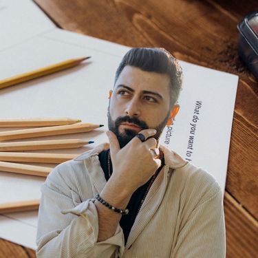 Lista papira s pitanjima i olovke na stolu uz muškarca koji razmišlja