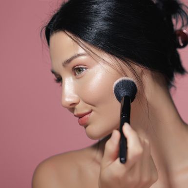 Žena nanosi puder kistom