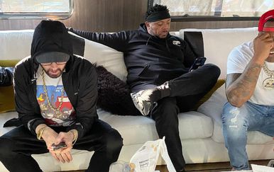 DJ Whoo Kid i reperi Eminem i Mr. Portera iz grupe D12 sjede na kauču na i gledaju na mobitel