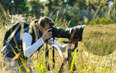 Fotograf u prirodi i mladunče lava skriveno u visokoj travi