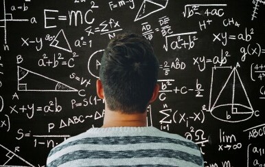 Muškarac kako razmišlja ispred ploče s matematičkim formulama