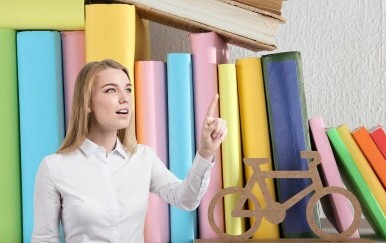 Žena koja diže ruku na pozadini od knjiga