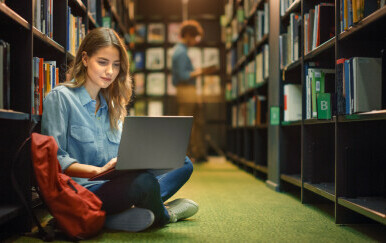 Djevojka s laptopom u knjižnici.