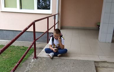 Dječak ispred škole čeka pomoćnika u nastavi (Foto: Facebook)