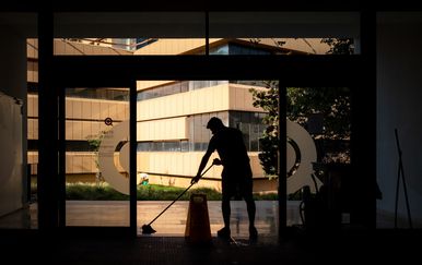 muškarac čisti ispred ulaza u zgradu