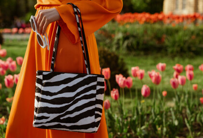 Žena u narančastom outfitu i s torbom sa zebrastim uzorkom